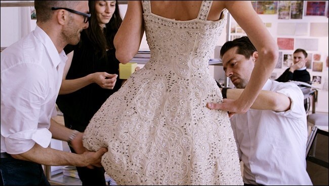 디올 앤 아이의 영화 장면 중 디올의 디자이너들이 모델에게 화이트 드레스를 입혀보면서 피팅하는 장면